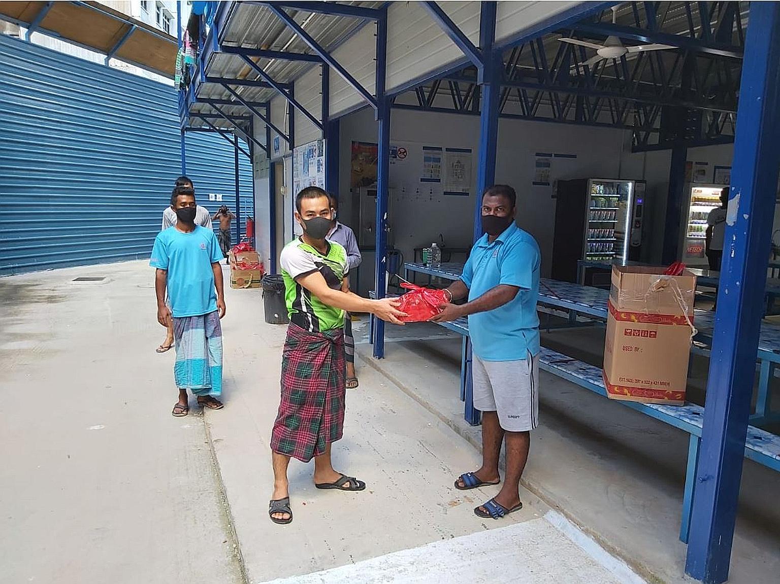 Two migrant workers with a Harvey Norman gift pack containing a portable fan and snacks at their dormitory last Saturday.