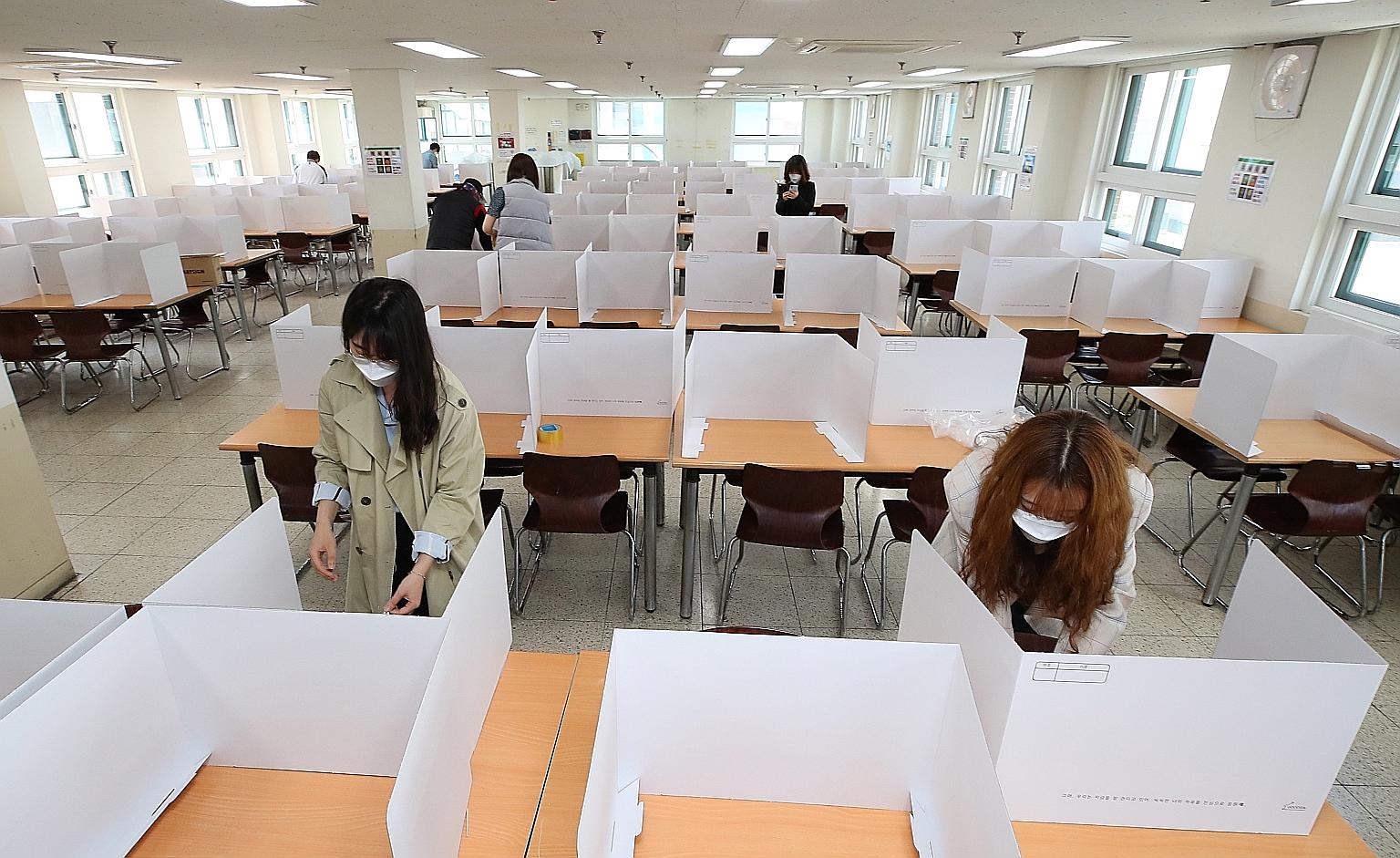 Teachers setting up dividers on tables in a cafeteria at the Duksoo High School in Seoul yesterday to get the school ready for reopening next Wednesday. Incheon city is on high alert for mass infections, after a 25-year-old teacher and resident was f