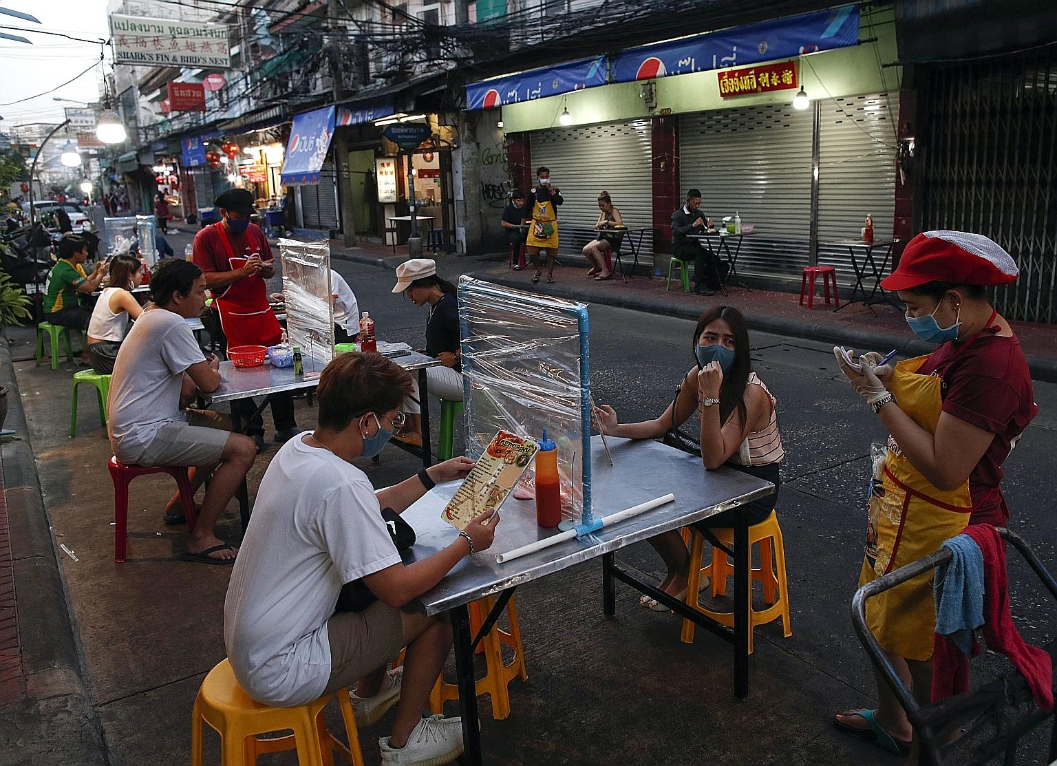 People dining at tables with plastic dividers meant to prevent the spread of the coronavirus, in Bangkok on Tuesday. The Thai government has begun gradually easing its stringent lockdown this month as the number of Covid-19 infections in the country 