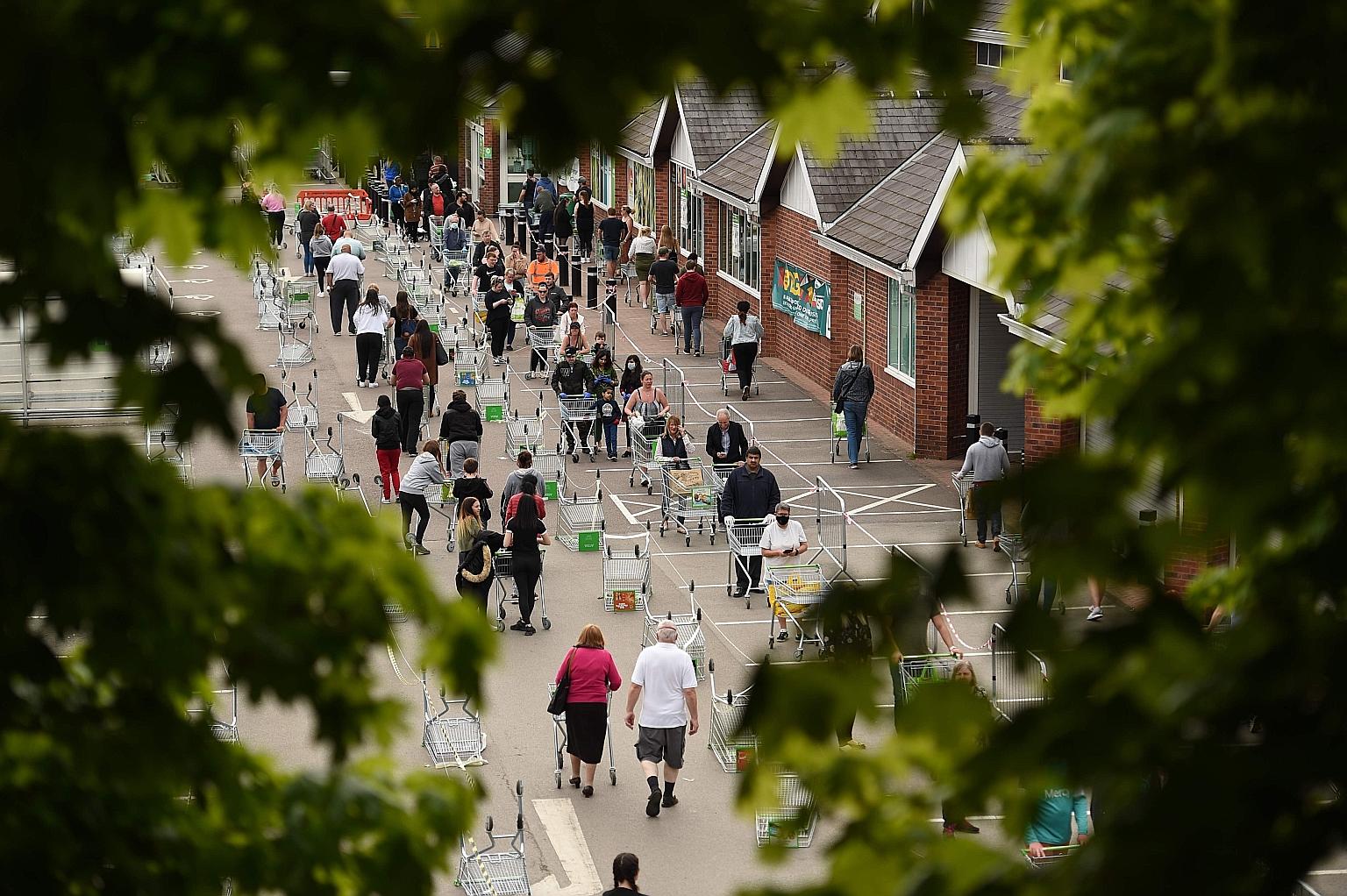 Customers practising social distancing while waiting to enter a supermarket in England last month. WHO's regional director for the Western Pacific, Dr Takeshi Kasai, says what countries and people must do is "to find a way to live with this virus for