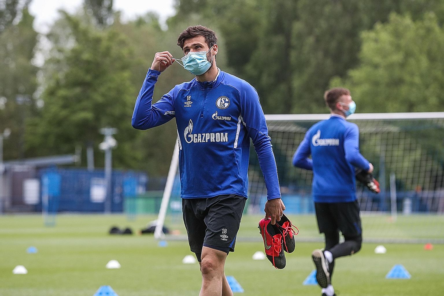 Schalke midfielder Daniel Caligiuri wearing a mask as he leaves the pitch after a session at the German club's training ground in Gelsenkirchen. Schalke face Borussia Dormund in the Bundesliga's restart today.