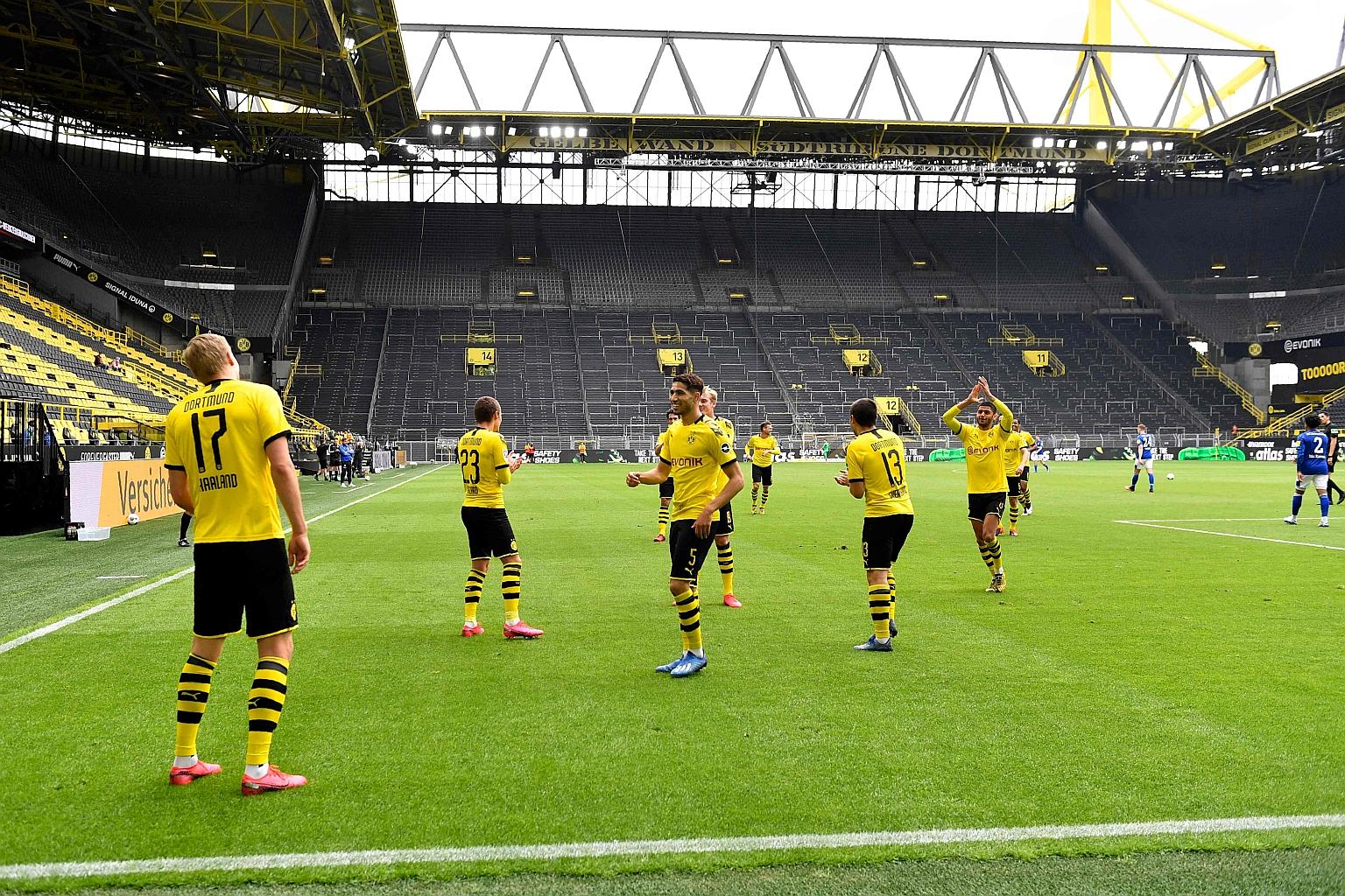 Borussia Dortmund's players amusing themselves with a celebration inspired by social distancing guidelines after Erling Haaland (No. 17) scored the opener against Schalke yesterday in a Signal Iduna Park devoid of its usual yellow wall of fans. The p