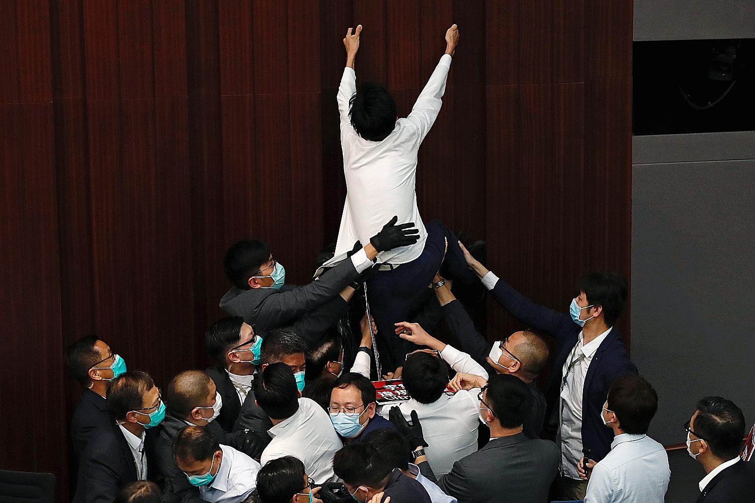 Pan-democratic legislator Eddie Chu Hoi-dick being hauled down by security officers and pro-government legislators during a House Committee meeting in Hong Kong yesterday.