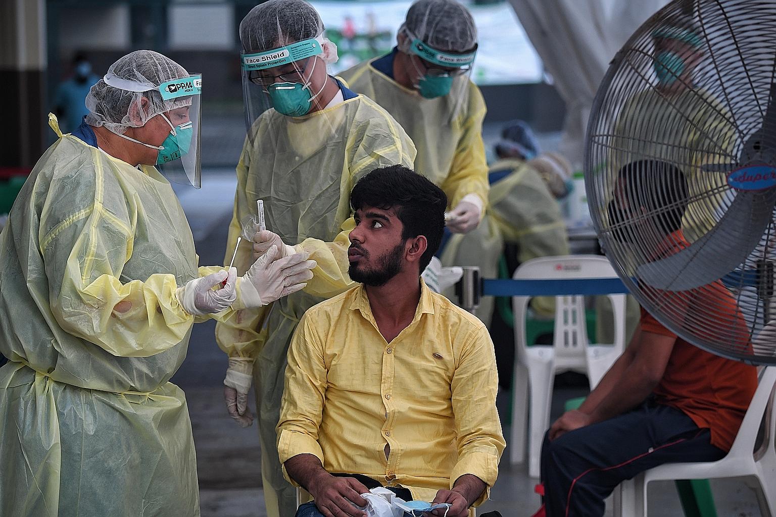 A medical worker explaining the swab test procedure to a foreign worker with Covid-19 symptoms at the on-site medical facility in Avery Lodge dormitory last week. Swabber, swab assistant and site supervisor positions are among the 1,500 openings that