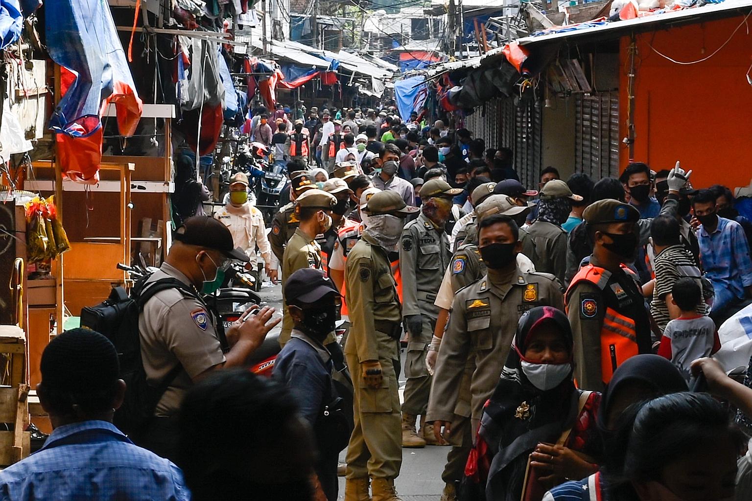 Indonesian police yesterday conducting an operation against clothes vendors in a market area who were defying a partial lockdown in Jakarta. PHOTO: AGENCE FRANCE-PRESSE
