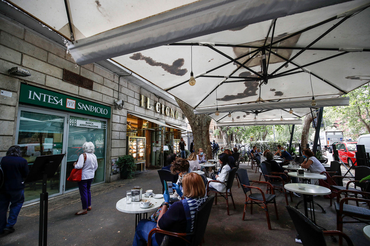 Malaysians shopping in Kuala Lumpur yesterday. Malaysia eased controls on May 4, allowing most businesses to reopen. But large gatherings are still banned. PHOTO: REUTERS Italians having coffee on the terrace of an eatery in Rome yesterday. Italy's b