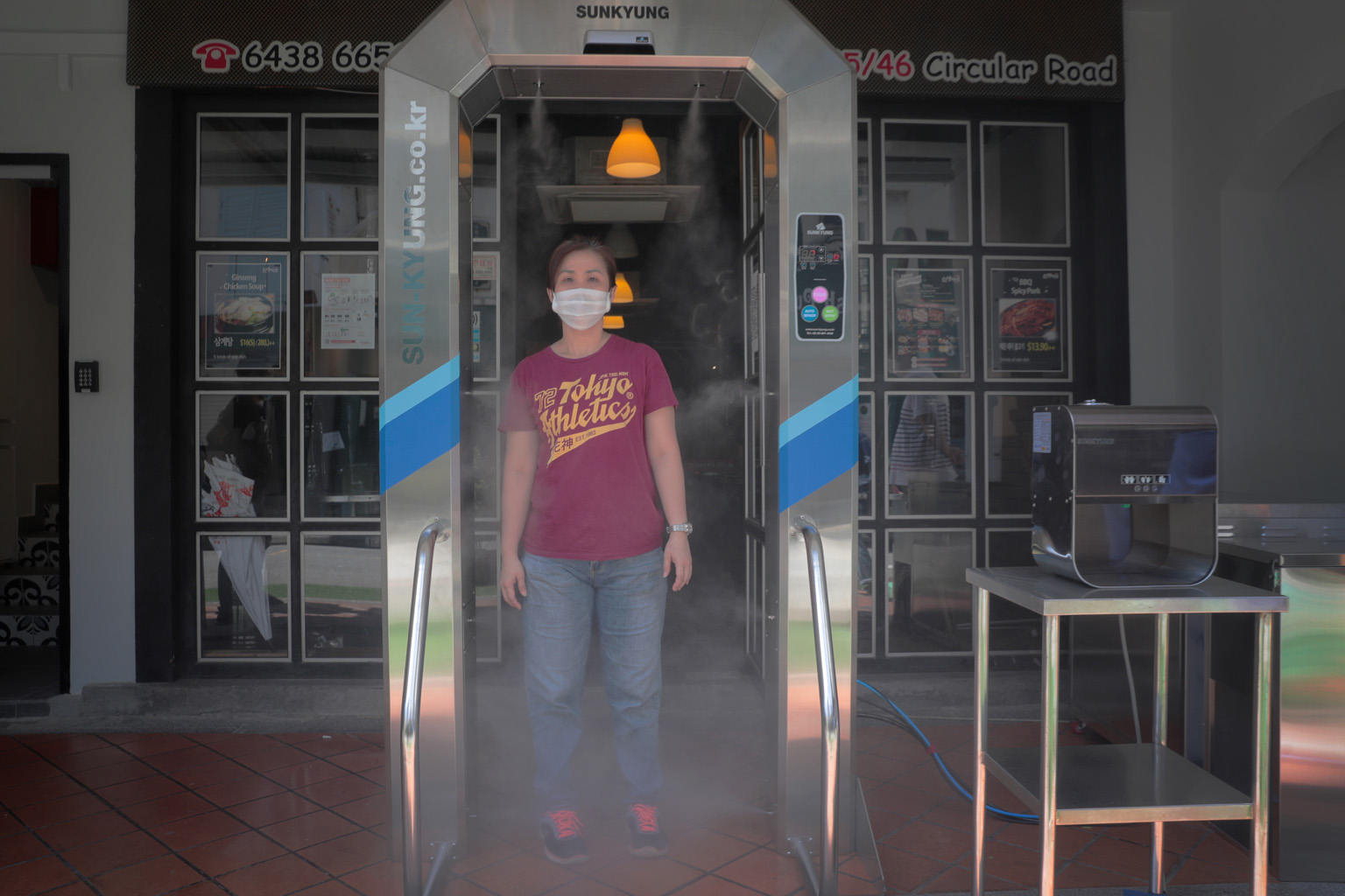 Waitress Erlinda Chia, 45, demonstrating the use of a disinfection tunnel at Hello Korean BBQ restaurant. Two firms providing such tunnels here say they use non-toxic disinfectants which are safe for people.