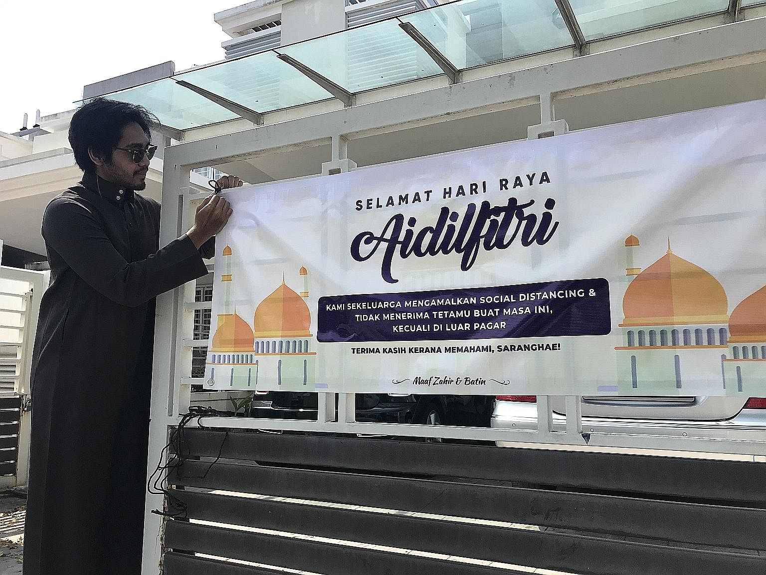 Mr Ahmad Afif Zainol putting up a Hari Raya banner outside his home in Alam Impian, Selangor. It comes with the message that the family is not accepting visitors amid the coronavirus pandemic.