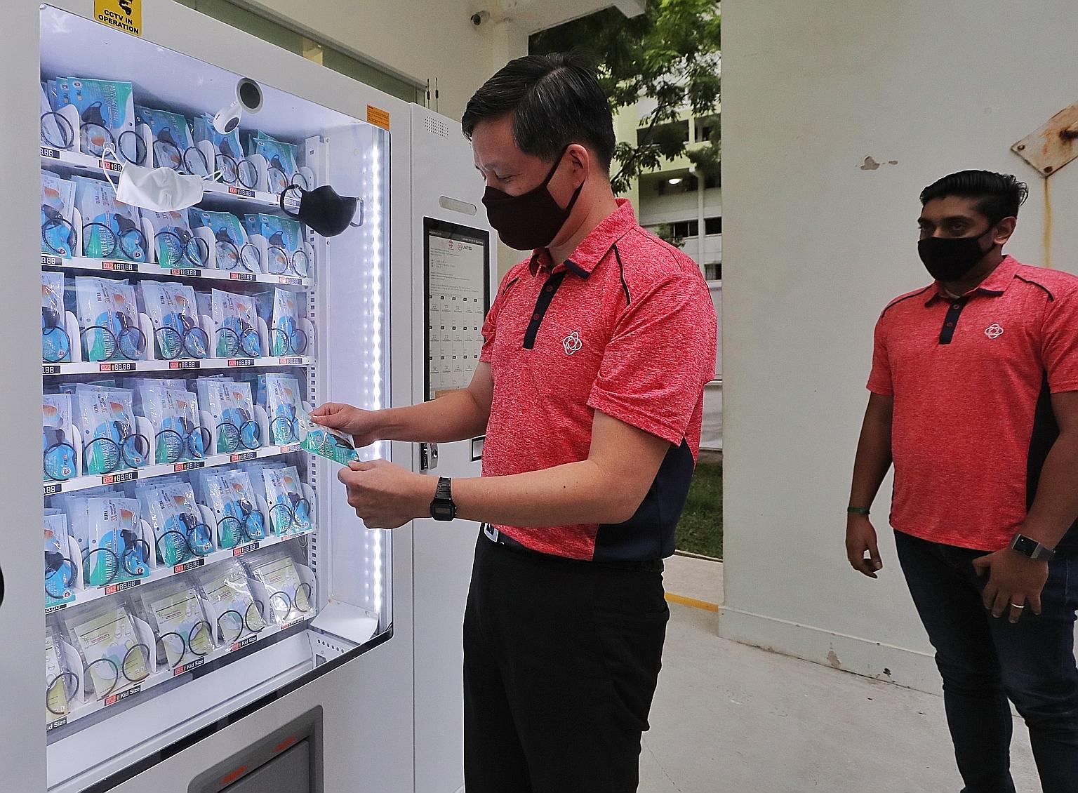 Trade and Industry Minister Chan Chun Sing holding a mask from a vending machine at Pek Kio Community Centre yesterday. About 400 of these machines will be placed at all community clubs for those who are unable to pick up their free masks from collec
