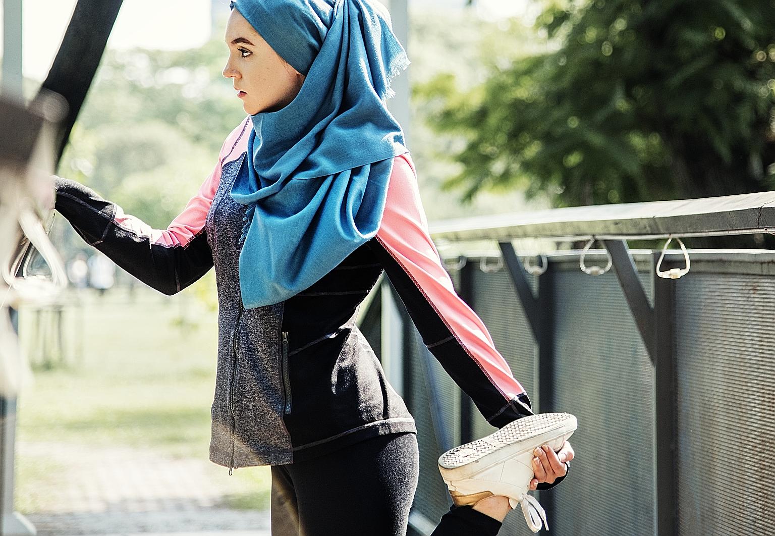 A Muslim woman stretching after a workout at the park. For some, faith and fitness intersect in the form of Ramadan boot camp workouts and Christian detox diets. PHOTO: ISTOCK