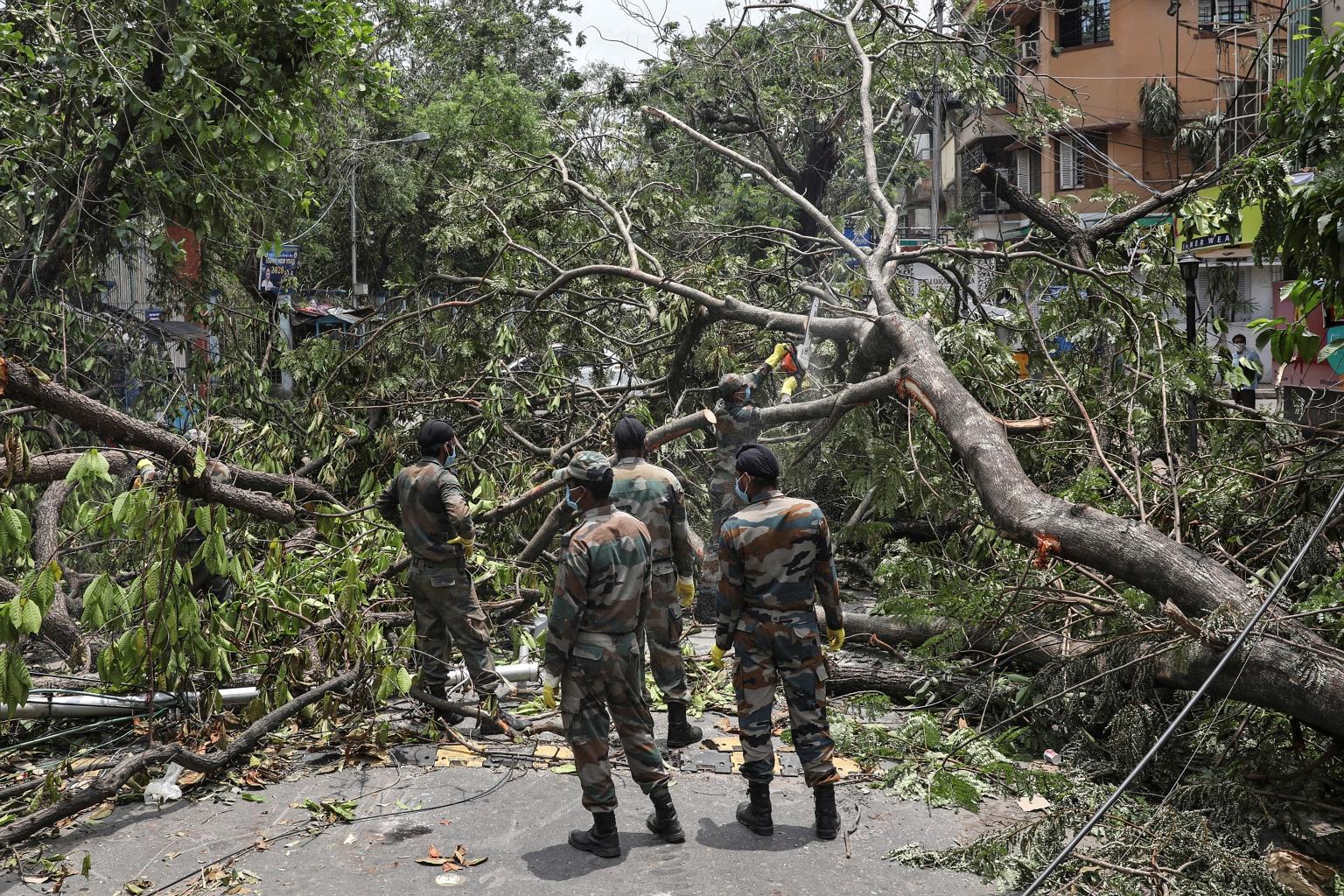 Indian soldiers helping to clear away uprooted trees in Kolkata, in the aftermath of Cyclone Amphan, yesterday. About 200 soldiers joined more than 4,000 disaster relief personnel and local volunteers working on the streets, said a military officer.