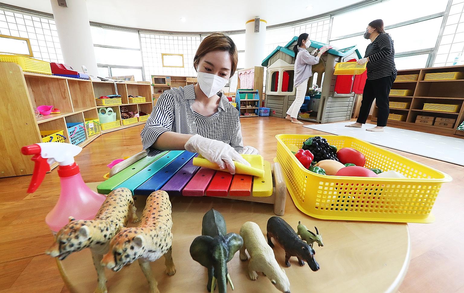 Teachers disinfecting toys at Hanil Kindergarten in Suwon, South Korea, yesterday. The country's second phase of school reopening begins today, with 2.37 million students, including kindergarteners and elementary school pupils, set to return. Many pa