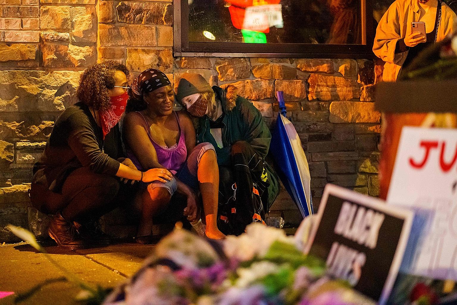 Mr George Floyd's girlfriend Shawanda Hill (centre) near the spot where he died while in police custody, on Tuesday in Minneapolis.