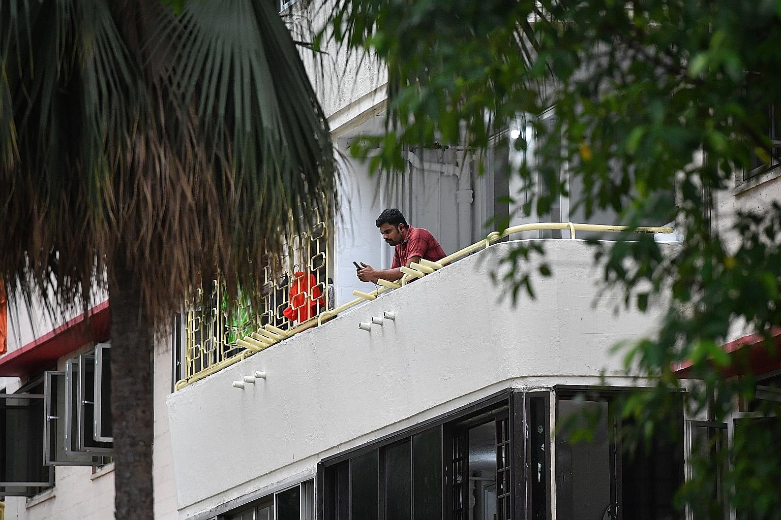 A man using his phone on a balcony in a block of flats in Redhill Close that is temporarily being used to house foreign workers. An initiative by Transient Workers Count Too, to help migrant workers top up their prepaid cards, has enabled workers to