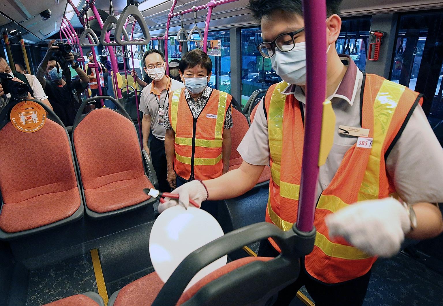 Transport Minister Khaw Boon Wan (centre) observing as a staff member removed a safe distancing notice from a seat on a bus at Ang Mo Kio Bus Interchange yesterday. PHOTO: LIANHE ZAOBAO