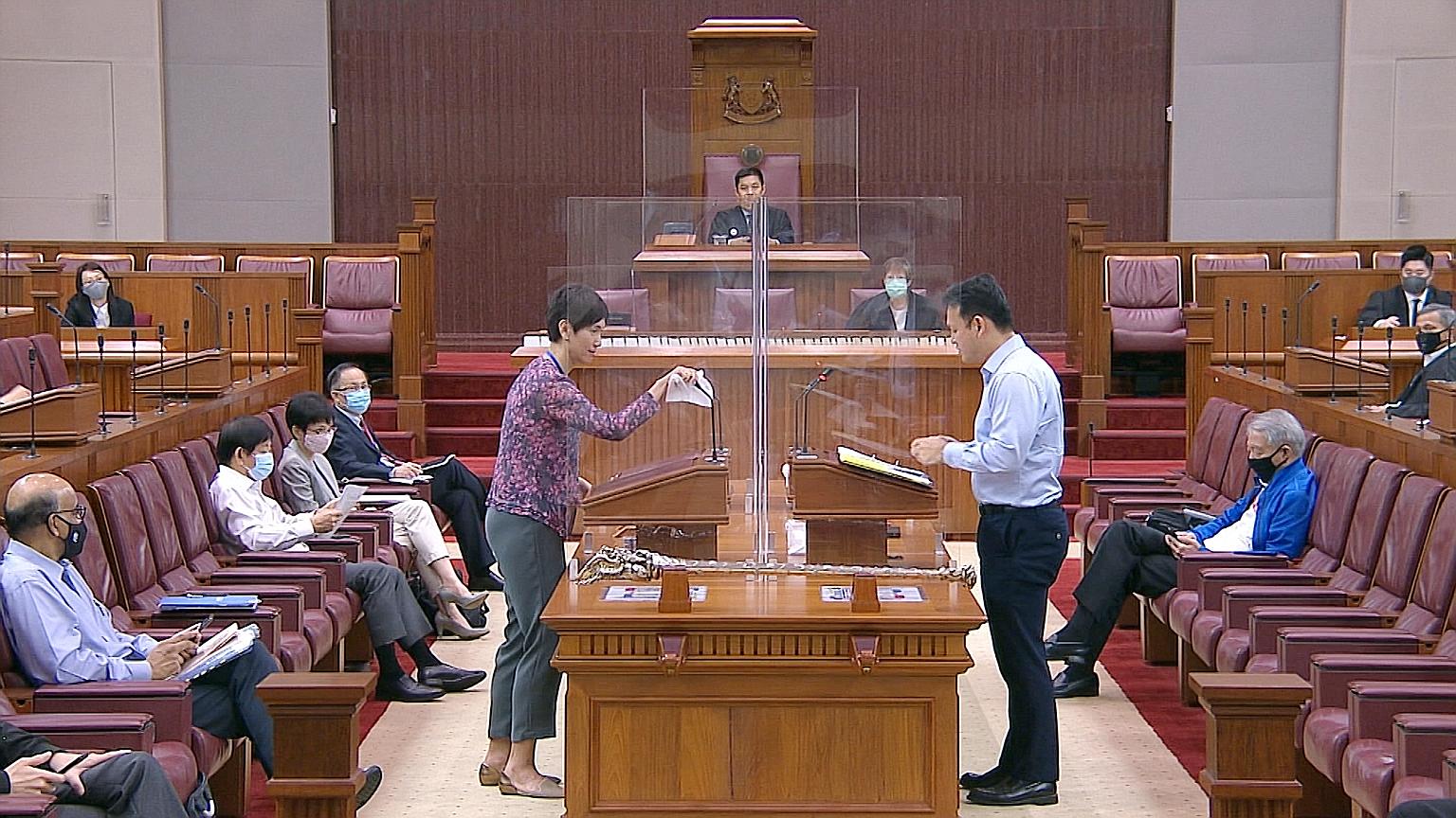 Manpower Minister Josephine Teo wiping down the microphone and podium after answering questions in Parliament yesterday as Minister of State for Manpower Zaqy Mohamad stepped up to speak. Perspex screens were set up in the House as part of safe dista