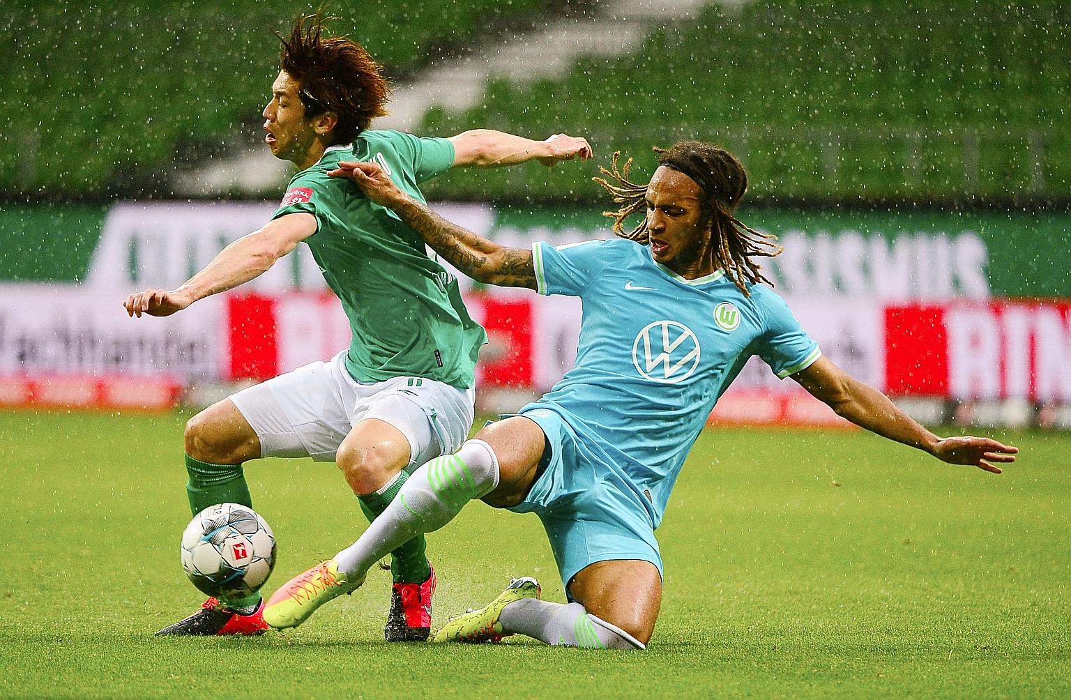 Wolfsburg defender Kevin Mbabu tackling Werder Bremen forward Yuya Osako during their Bundesliga game yesterday. Wolfsburg beat the hosts 1-0.