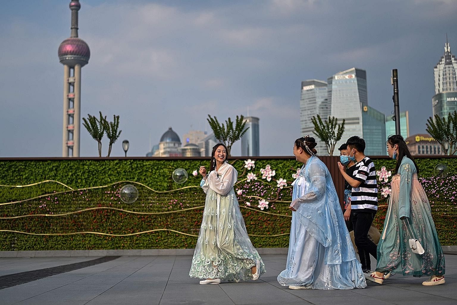 Young women in traditional dress at The Bund in Shanghai last Tuesday. China, being the first to face Covid-19, is now leading the world in getting a measure of control over it. Other markets in Asia and Europe are reopening in phases, and economic i