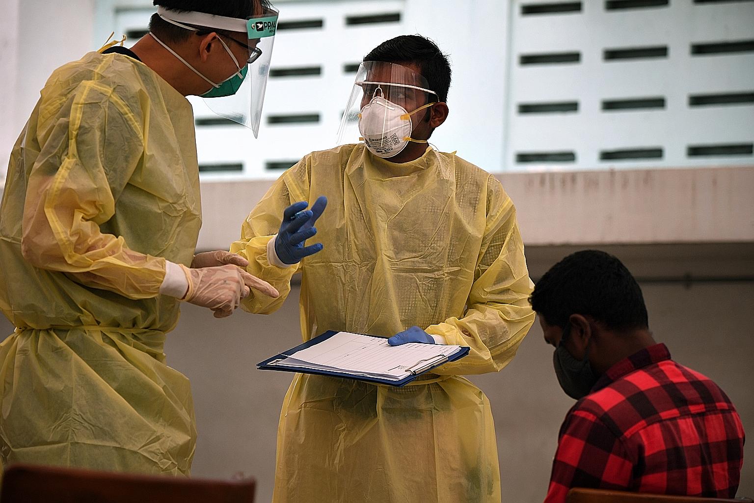 Migrant worker volunteer Rajendran Raja (centre) speaking to a medical worker at Homestay Lodge dormitory last Wednesday. Armed with a clipboard and dressed in full personal protective equipment, he is sometimes mistaken for a Fast (forward assurance