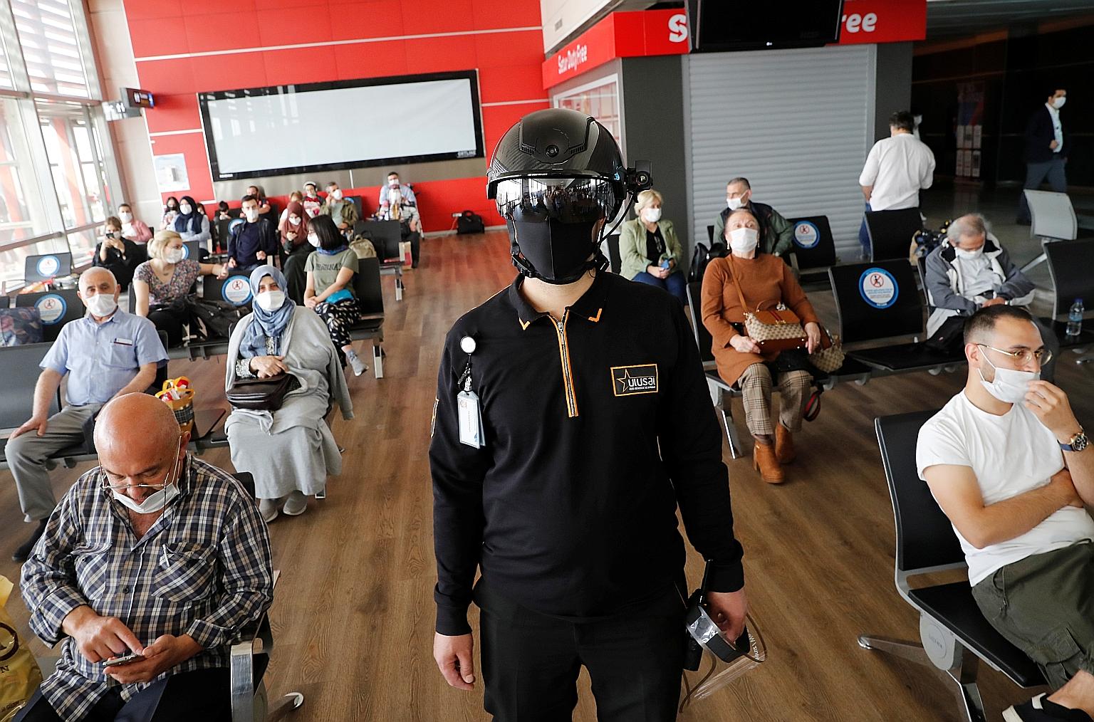 A security employee in a thermal-imaging helmet monitoring passengers as they waited to board an AnadoluJet flight to Stuttgart, Germany, at Istanbul's Sabiha Gokcen International Airport yesterday, the first day that Turkey resumed international fli