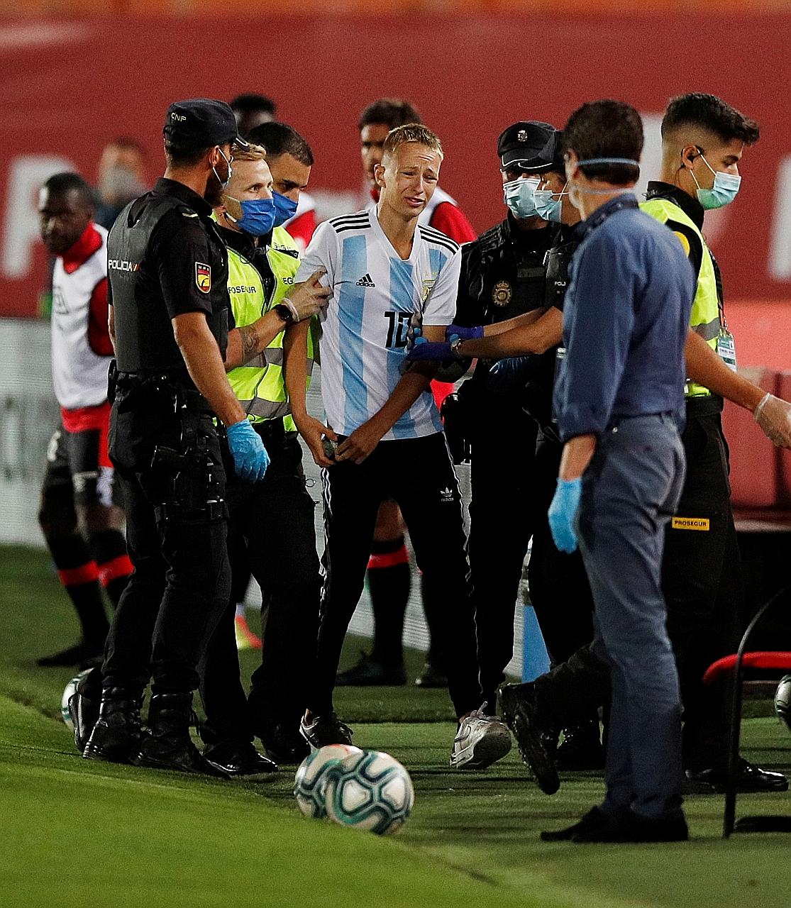 A French Mallorcan pitch invader is removed from the field of play at Son Moix Stadium.