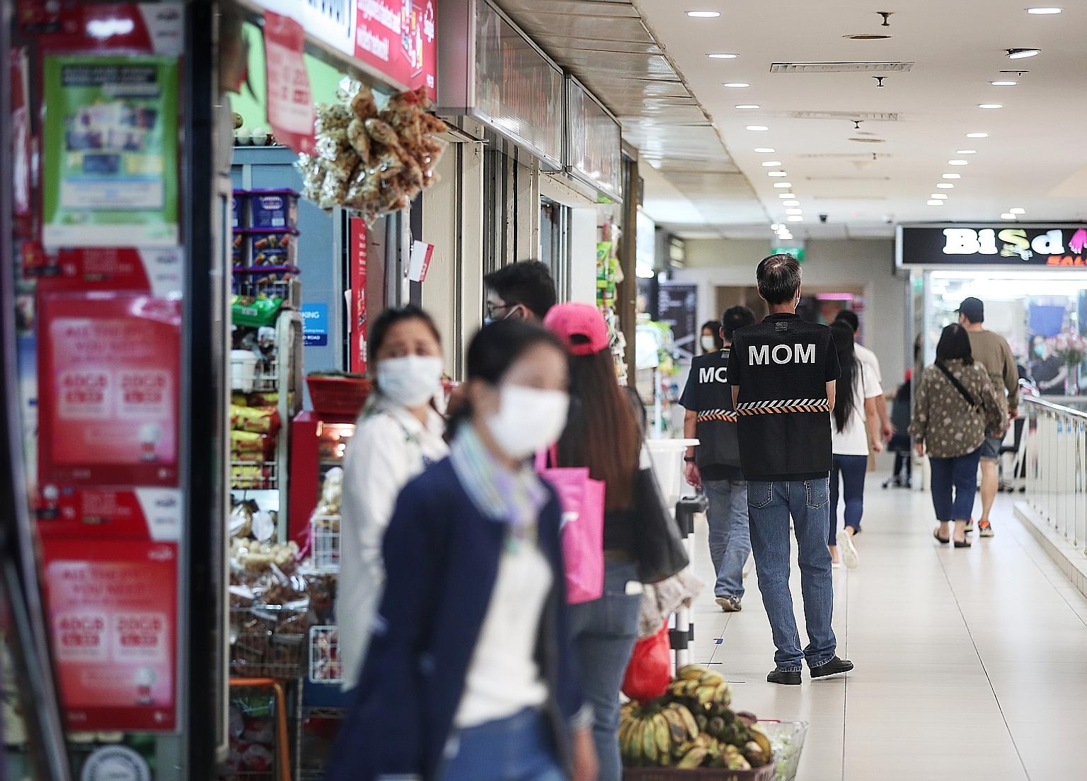 Enforcement officers from the Ministry of Manpower patrolling Lucky Plaza yesterday afternoon, with crowds notably thinner compared with the previous weekend. A new rule requiring those who want to remit money through agencies at Lucky Plaza, City Pl