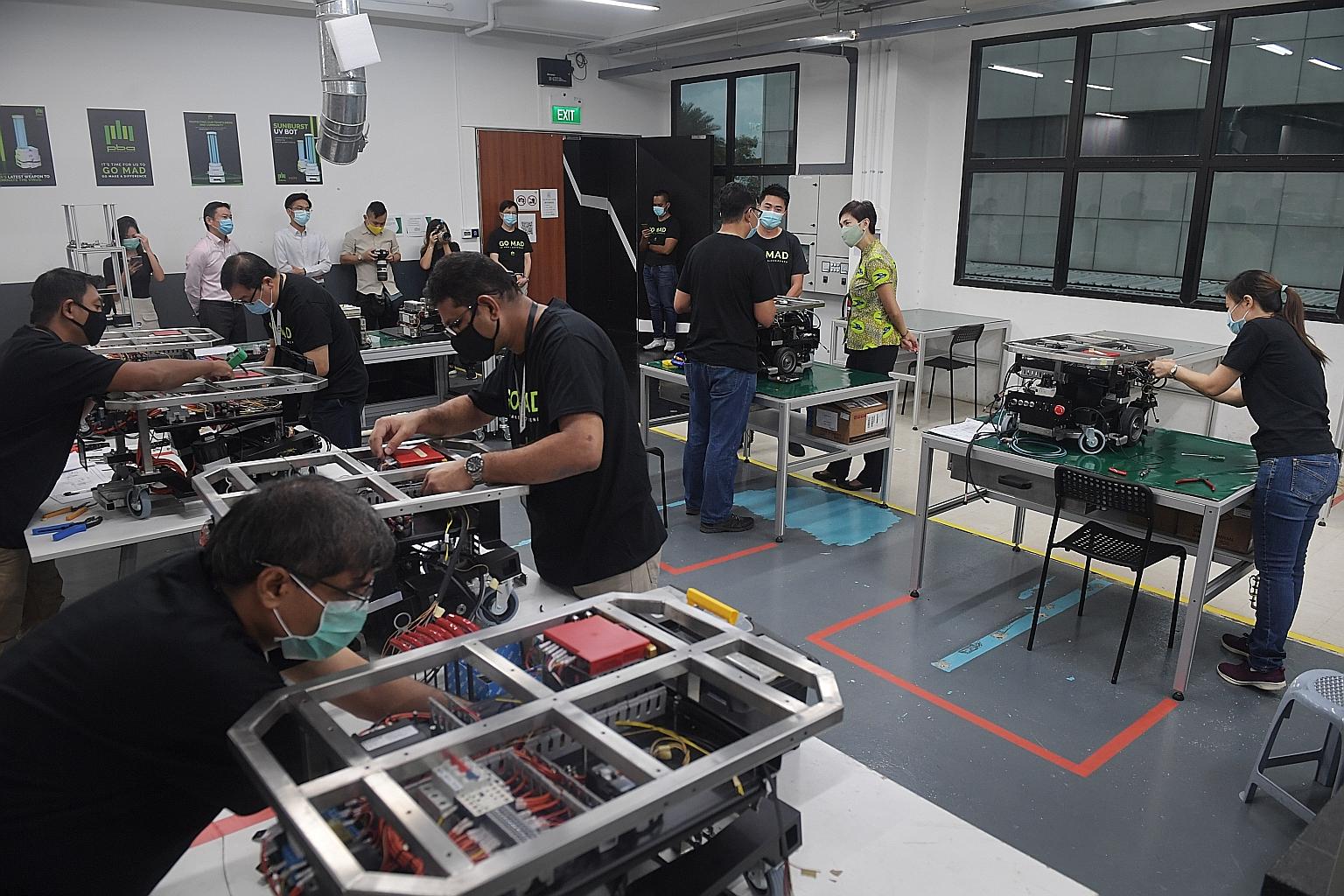 Manpower Minister Josephine Teo (far right) at the production facility of PBA Group, a robotics and automation company, in Yishun, where she met the firm's trainees. PBA has hired 13 staff under the attach-and-train programme for robotics engineers. 