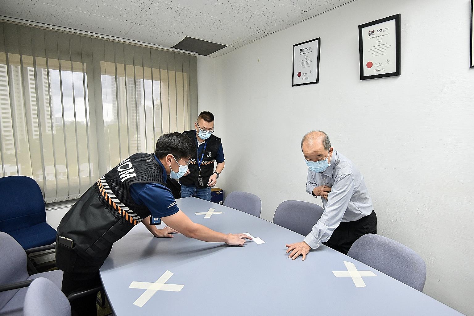 Ministry of Manpower officers giving advice on how to improve the implementation of safe management measures at a workplace. The ministry has inspected close to 1,000 workplaces as part of its enforcement operations.