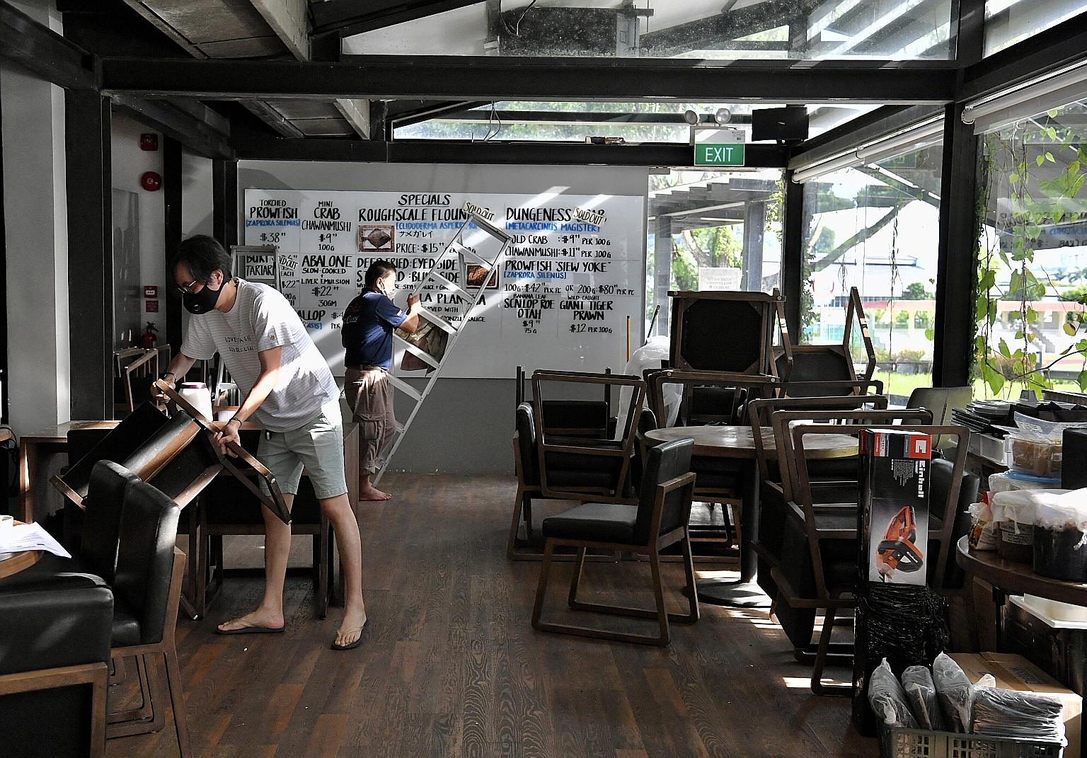 Naked Finn owner Tan Ken Loon (left), 45, setting up the tables and chairs in his eight-year-old seafood restaurant at Gillman Barracks yesterday as he got ready for the start of phase two tomorrow, when food and beverage outlets can restart dine-in