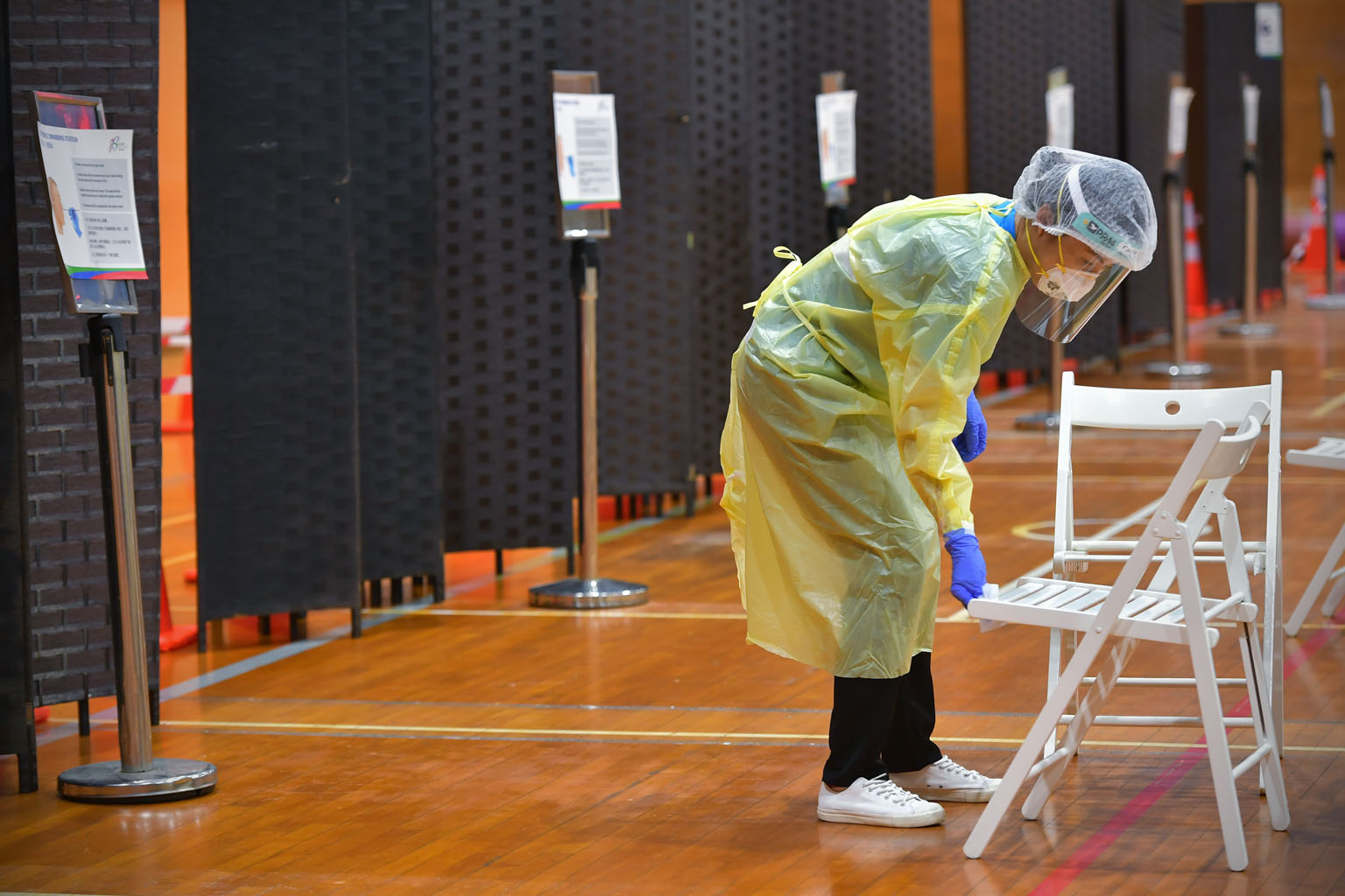 A swabber sterilising a seat in the Bukit Gombak Sports Hall, which has been designated a Regional Screening Centre. ST PHOTO: NG SOR LUAN