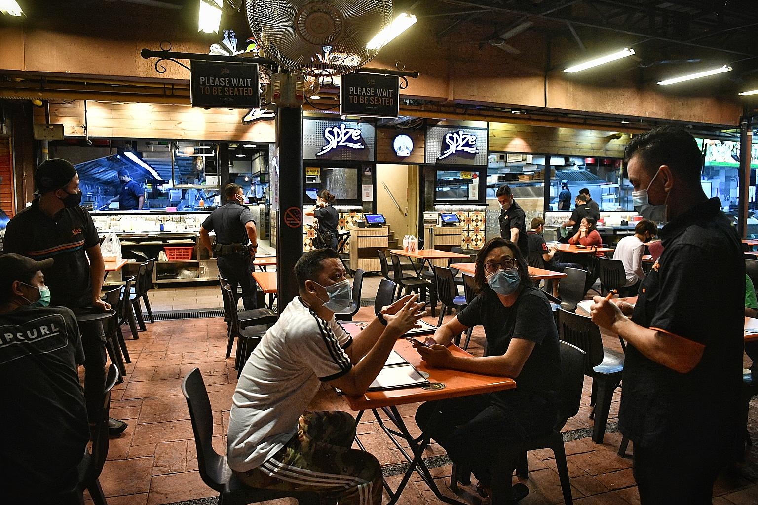 As phase two of Singapore's reopening began at midnight yesterday, patrons were quick to enjoy a spot of dining-in at Simpang Bedok - but not before getting their temperature checked, one of several measures to prevent the spread of Covid-19. ST PHOT