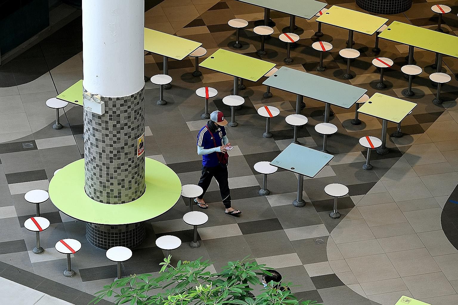 Seats at Our Tampines Hub Hawker Centre marked out yesterday with red tape to ensure safe distancing. Dining in will be allowed from today, as phase two kicks off. An employee at a store in Junction 8 in Bishan arranging products on Wednesday, ahead 