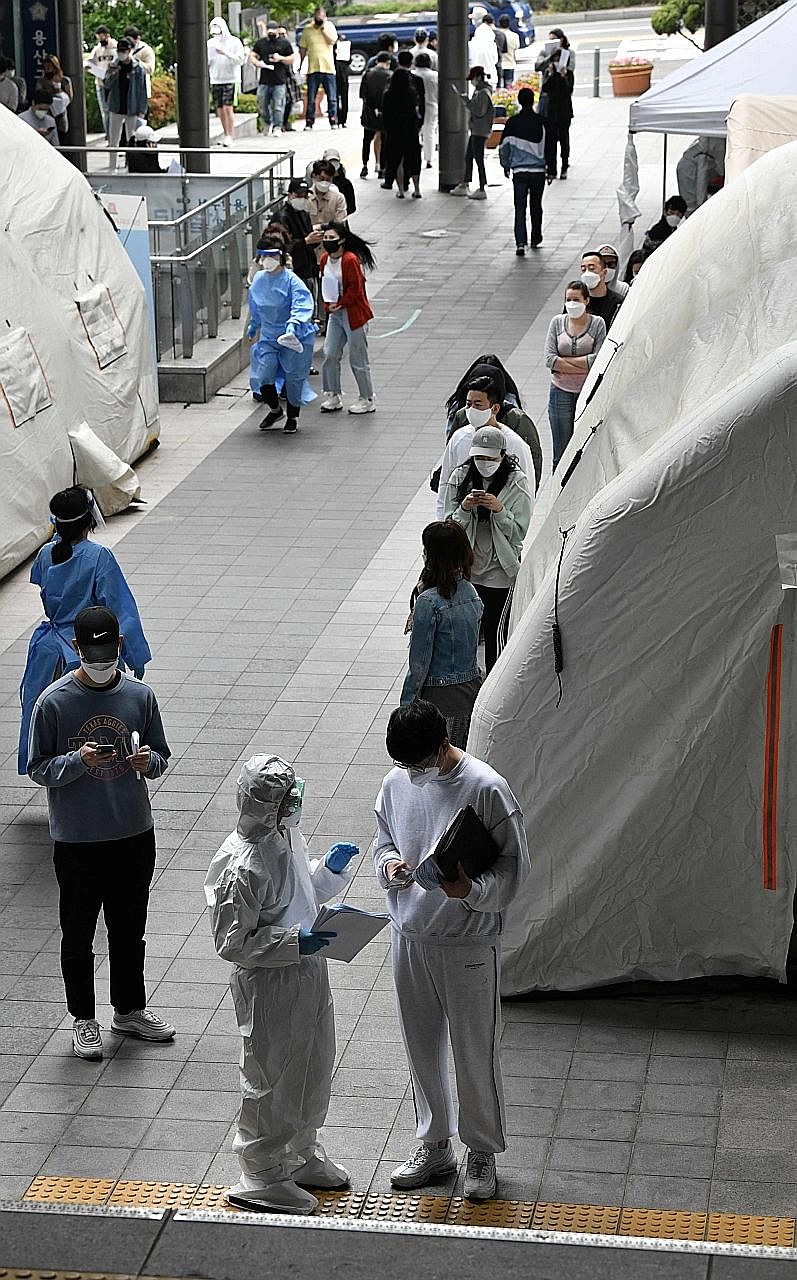 A member of a medical team speaking to one of the people waiting for a coronavirus test at a testing station in Seoul's nightlife district of Itaewon, where an outbreak of Covid-19 infections flared up recently. PHOTO: AGENCE FRANCE-PRESSE