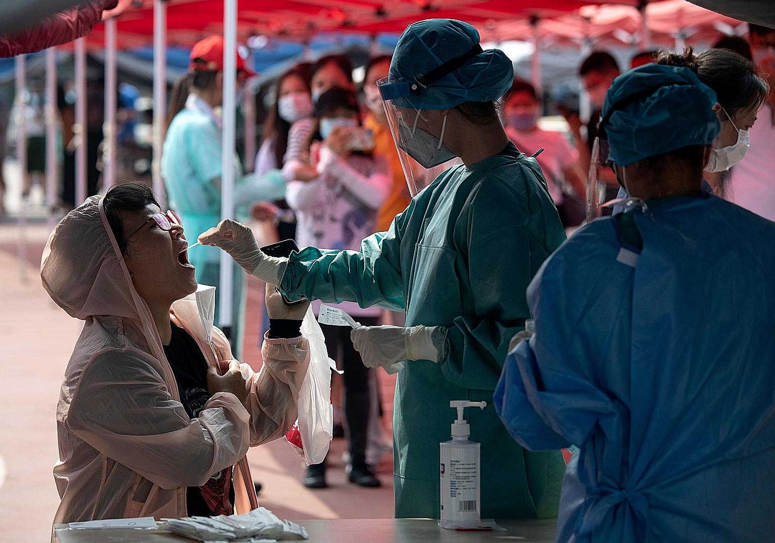 A health worker in a protective suit doing a swab test during mass testing for Covid-19 in Beijing yesterday. Officials said they are ramping up screening as the number of infections continues to rise.
