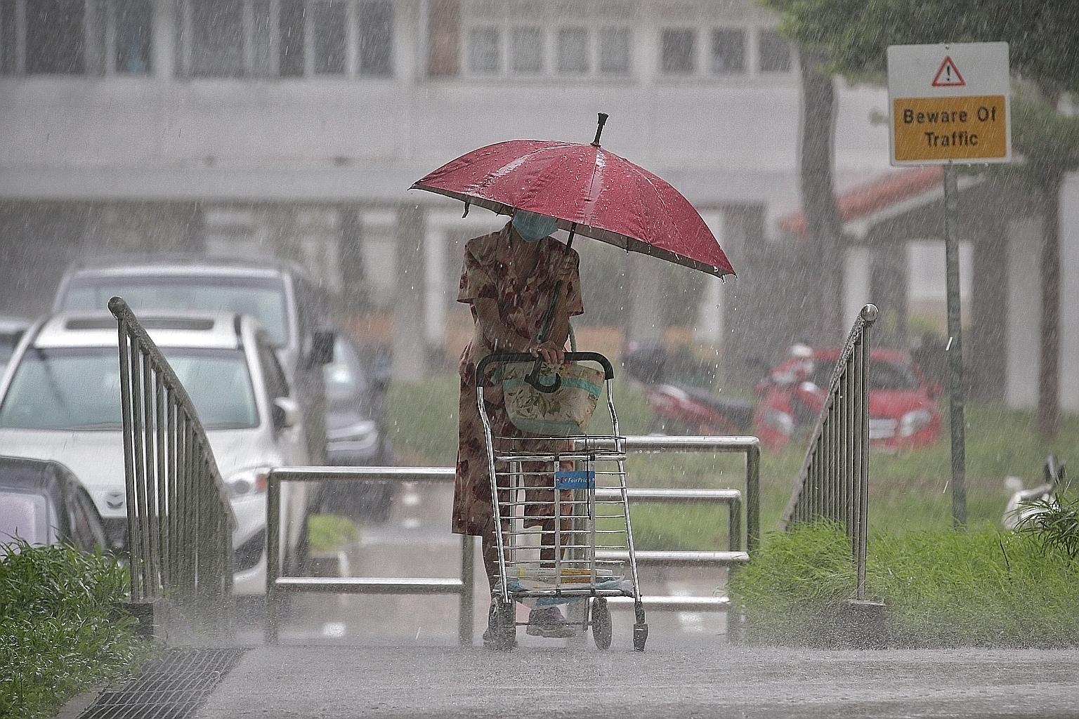 Singapore continued to experience heavy rainfall yesterday, including in Bedok South where this elderly woman is seen walking. Bedok South was hit by flash floods on Tuesday, recording rainfall of 108.8mm between 7.10am and 9.05am - which amounted to