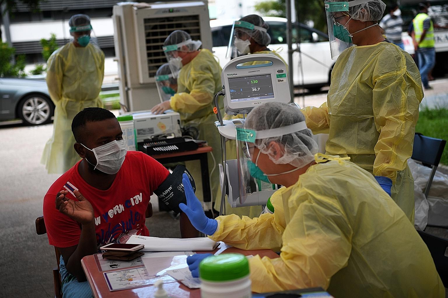 A worker consulting a medical doctor at Homestay Lodge dormitory in Kaki Bukit earlier this month. National Development Minister Lawrence Wong said about 70 per cent to 80 per cent of foreign workers staying in dormitories are expected to be cleared 
