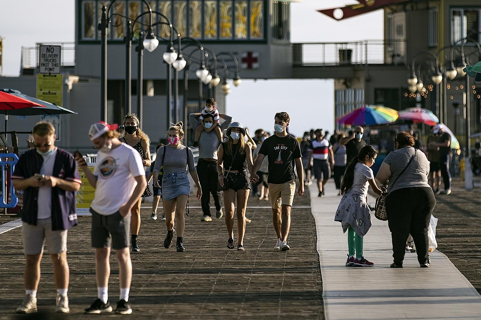 Strollers on the Santa Monica Pier in California on Thursday. Florida, California, Arizona and Texas account for almost half of all new Covid-19 cases now, an outsize proportion even after adjusting for their large populations. PHOTO: EPA-EFE