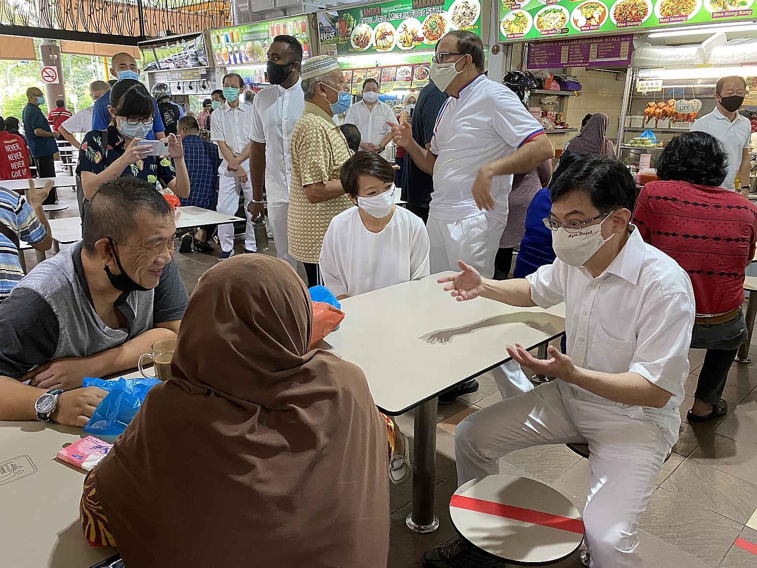 (From right) Deputy Prime Minister Heng Swee Keat (seated), Communications and Information Minister S. Iswaran and West Coast GRC MP Foo Mee Har met members of the public around Teban Market Place yesterday.