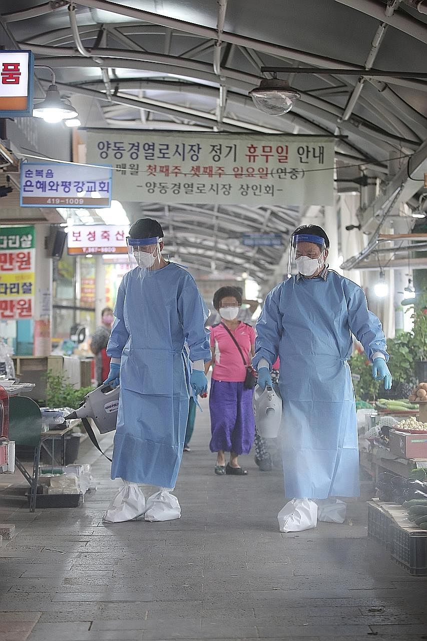 Quarantine officials disinfecting a market in Gwangju city, South Korea, yesterday. At least 12 virus cases have been traced to the Gwangleug Temple in south-western Gwangju city, including a monk and worshippers.