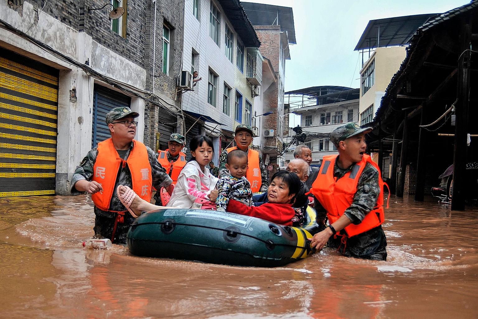 Rescuers evacuating residents in a flooded area in China's south-western Chongqing in this photo taken on Sunday and released yesterday. It was the municipality's worst flood since 1940. 	China's national observatory yesterday renewed its blue alert 