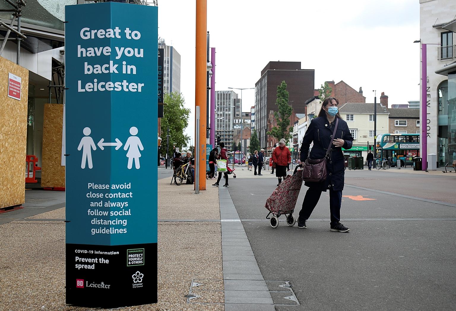 A woman wearing a protective face mask in Leicester yesterday. A spike in coronavirus cases in the English city has put it back under lockdown. The city's seven-day infection rate was 135 cases per 100,000 people, three times higher than the next hig