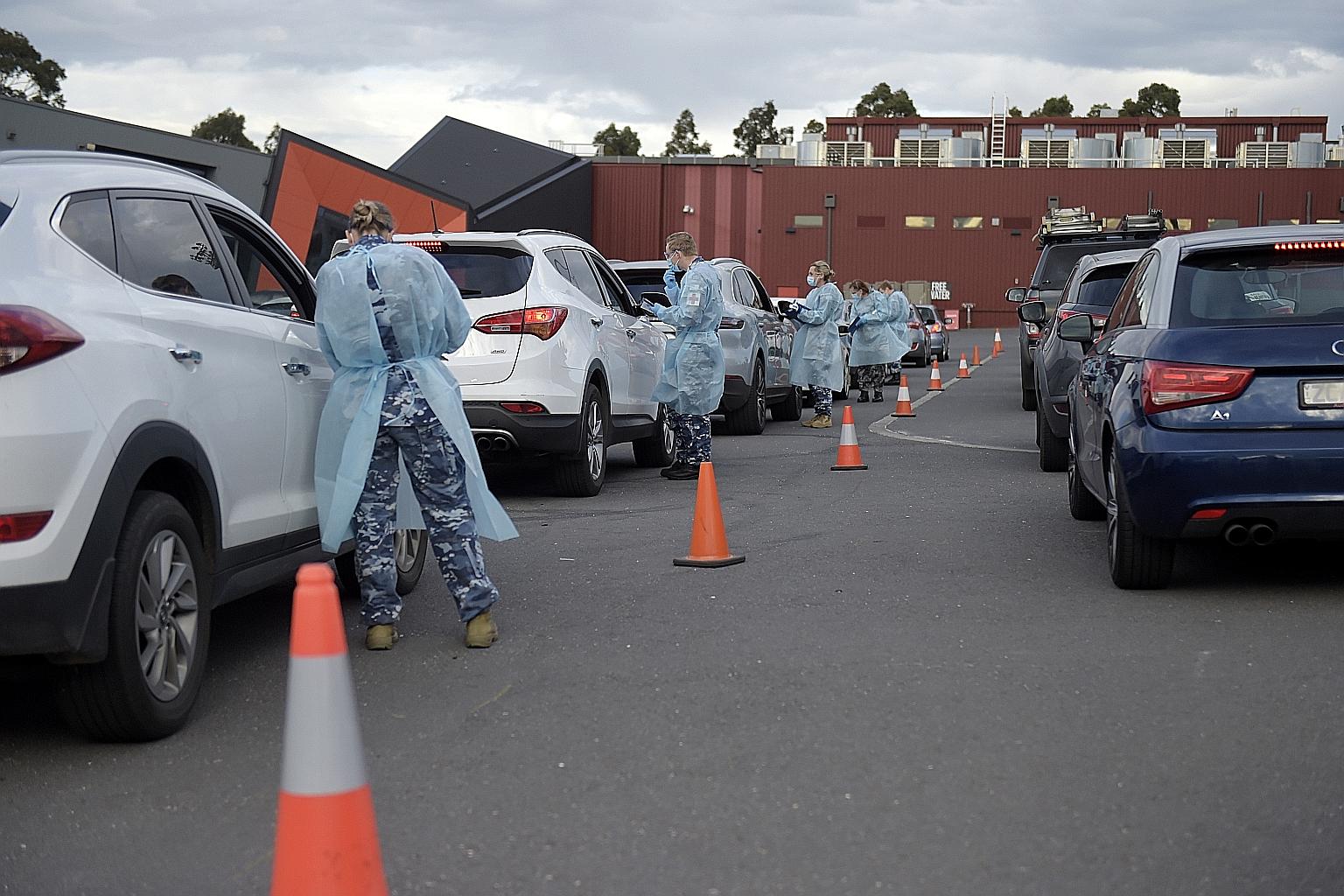 Members of the Australian Defence Force gathering information and checking temperatures of people at a drive-in Covid-19 testing site in Melbourne yesterday.