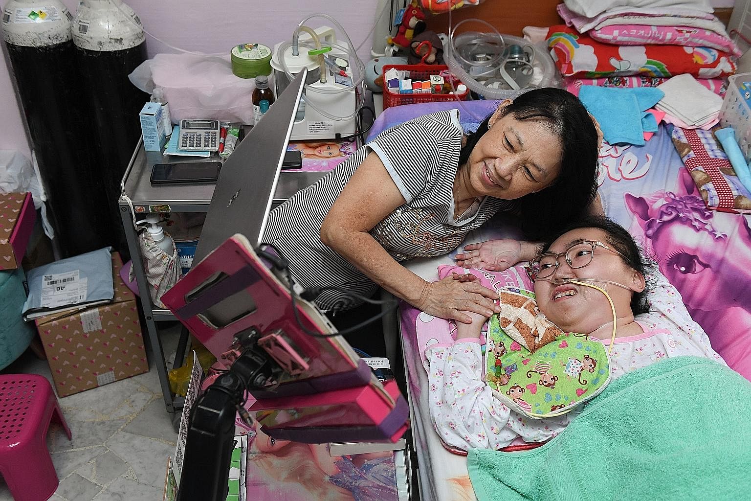 Although she suffers from spinal muscular atrophy type 2 and is confined to her bed, Miss Vivian Goh, seen here with her mother Ivy Yong, is able to run an online business, play online games, watch YouTube videos and attend online church services on 