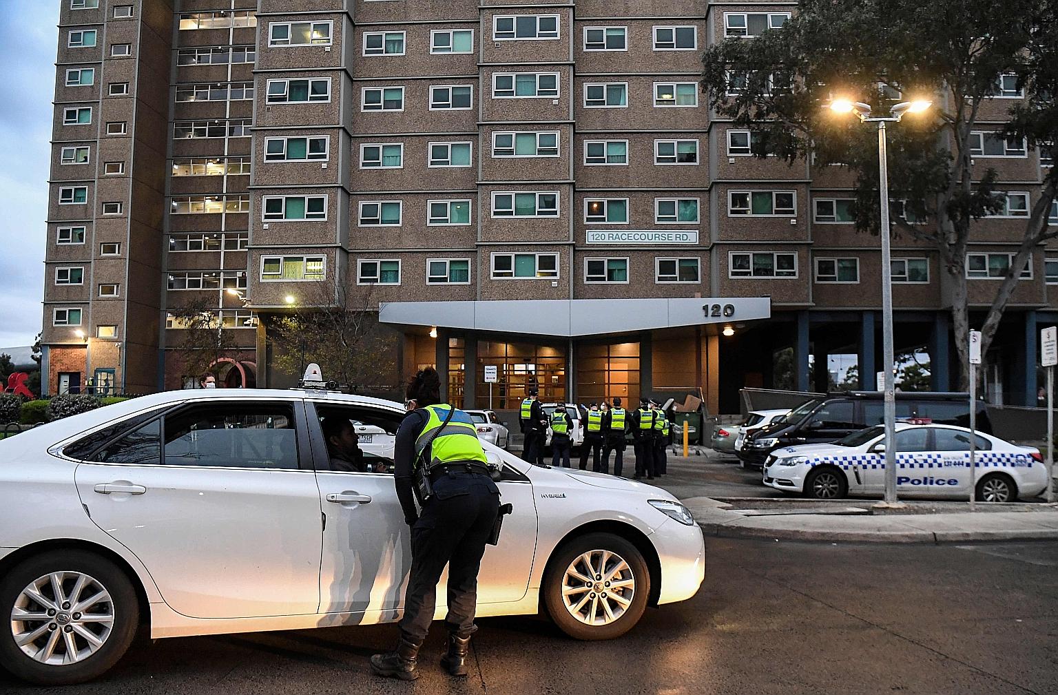 A woman (above) speaking to police officers yesterday after attempting to leave a public housing tower in Melbourne, the capital of the Australian state of Victoria. The police are enforcing a five-day lockdown of nine public housing towers (left) in