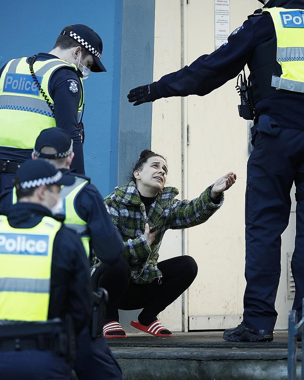 A woman (above) speaking to police officers yesterday after attempting to leave a public housing tower in Melbourne, the capital of the Australian state of Victoria. The police are enforcing a five-day lockdown of nine public housing towers (left) in