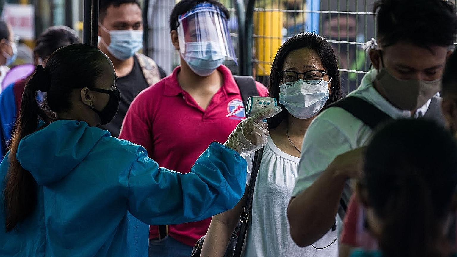 A passenger having her temperature taken before boarding a bus at a station in Manila yesterday. Even after the three-month lockdown was lifted on June 1, the Philippine government was forced to shut down the Metro Rail Transit in Manila, the capital