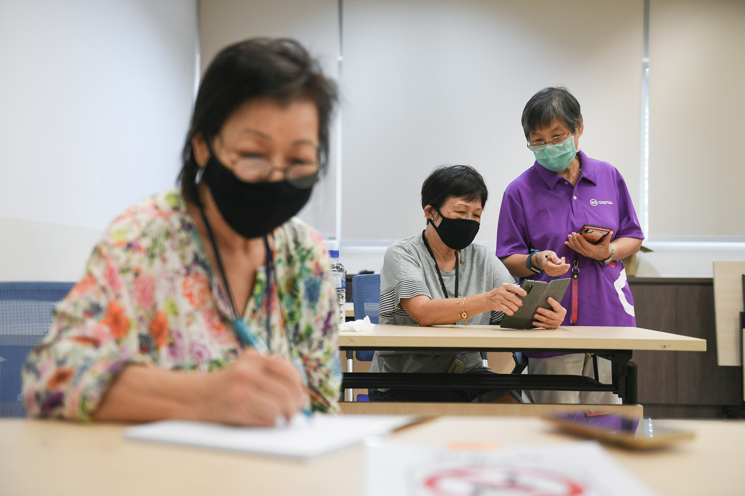 Retirees Audrey Goh (far left), 70, and Teresa Fong, 74, learning about Zoom video-conferencing from SG Digital ambassador Yeo Beng Choon, 73, yesterday at West Coast Community Centre, which is one of five SG Digital community hubs that have already 