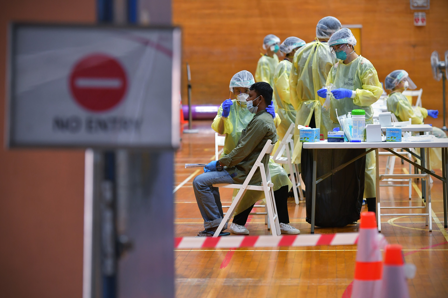 A man going through a swab test for the coronavirus last month at a regional screening centre set up in a sports hall in Bukit Gombak. About 80 per cent of the 323,000 workers living in dorms here are expected to have recovered from Covid-19 or to te
