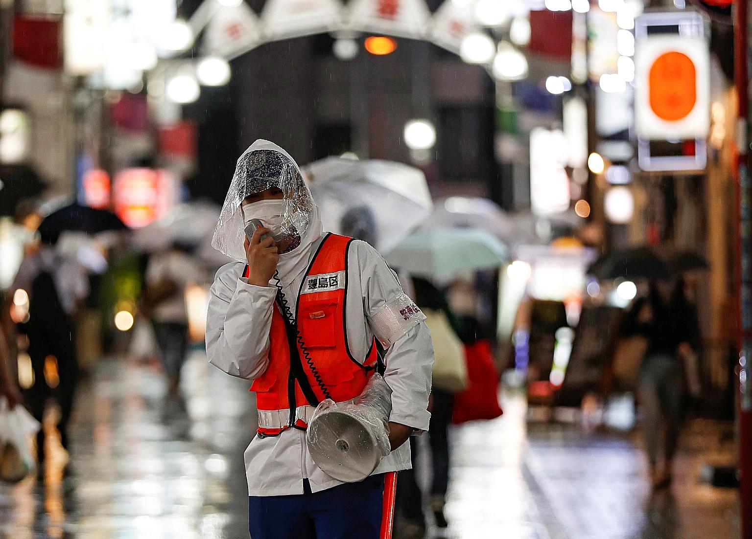 A security person in Tokyo reminding people about measures against the coronavirus. Japan is trying to balance containment efforts with economic revival. PHOTO: REUTERS