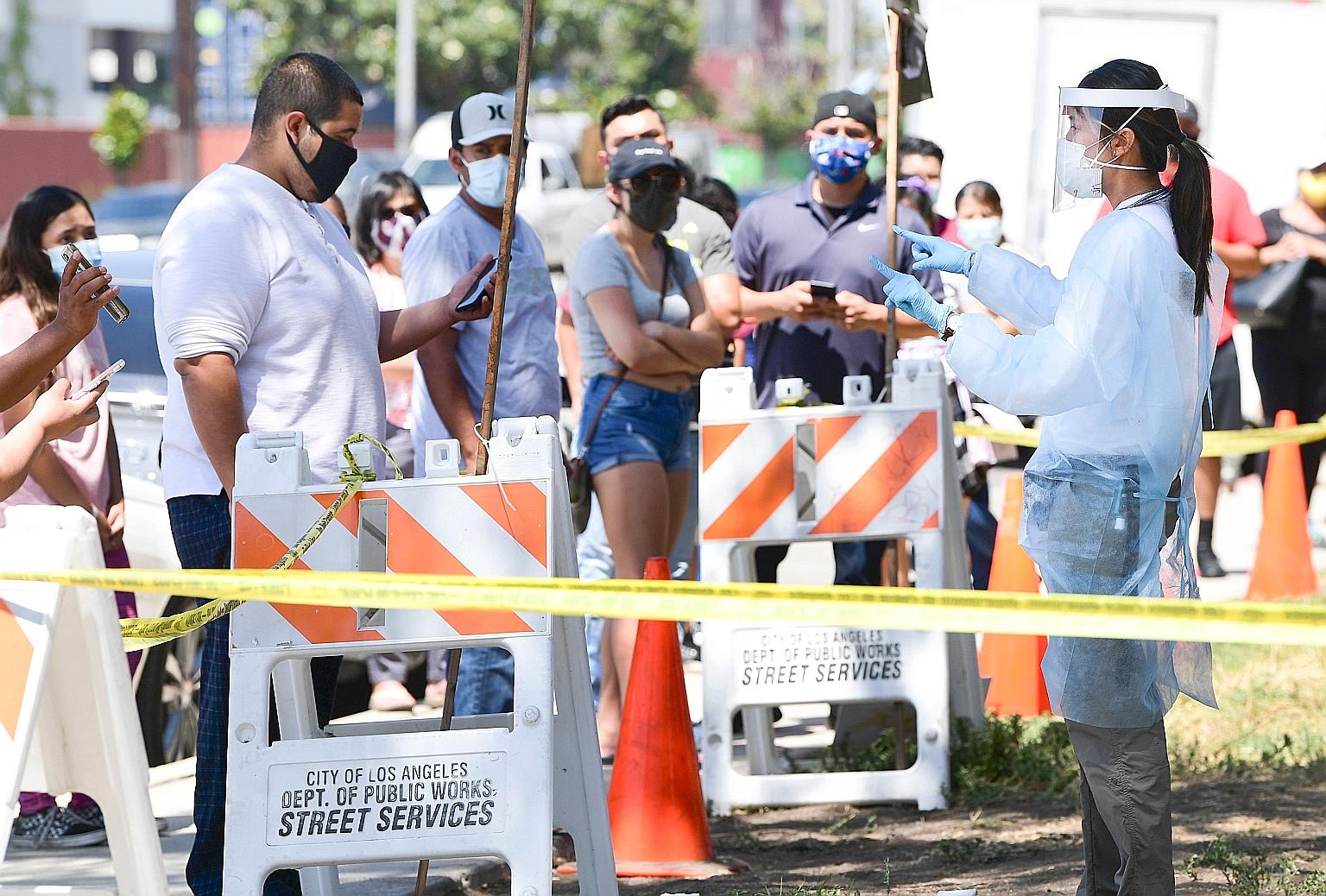 A volunteer in personal protective gear advising people at a coronavirus test site in Los Angeles. Nine states reached records in single-day infections as new cases rose by more than 69,000 across the US.